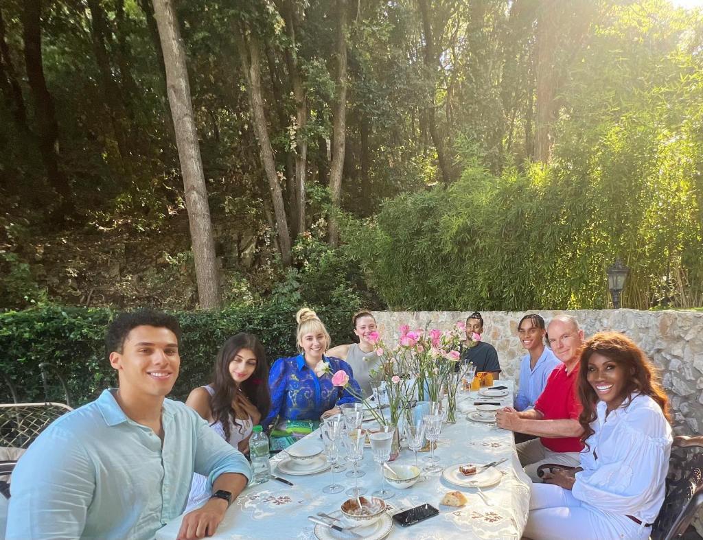 Prince Albert of Monaco with his adult children Alexandre and Jazmine Grace Grimaldi at a dining table outdoors.